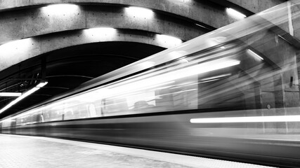 Black and white long exposure photography of a subway train in motion in a station