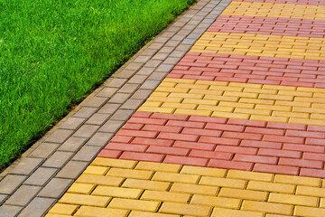 Fototapeta premium walkway made of paving slabs and green grass as a background, bright sunlight