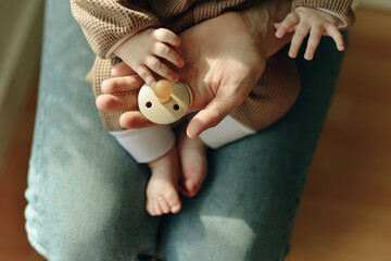 baby holds a pacifier in his mother arms