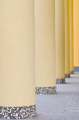 Fragment of facade of a light yellow building with big round columns.  Selective focus.