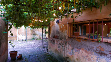 patio interior de casa de campo, cubierto con glicinias y adornado con guirnaldas de luces   