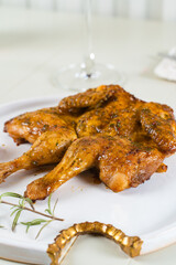 Tobacco chicken on a white plate with a glass of red wine, cutlery. Grilled chicken.
