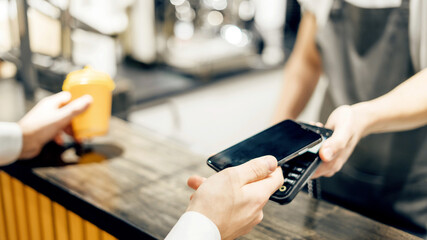 NFC technology a male customer pays the bill via a smartphone using. A mobile phone with...