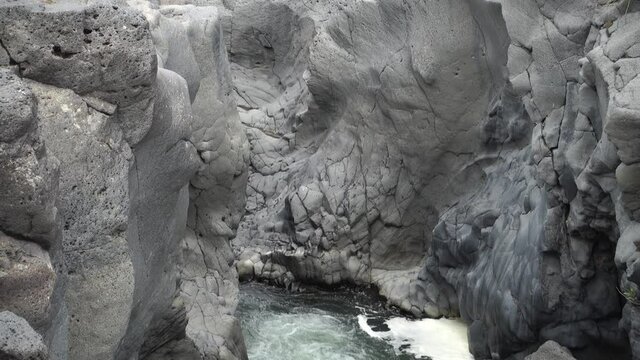 volcanic rock of Sicily nature split by a fault and smoothed by the waters flowing in a gorge of Simeto river 