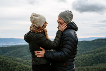 Woman touching smiling boyfriend's cheeks against sky