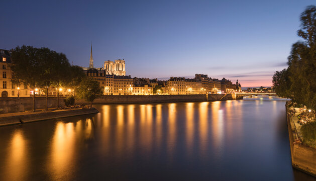 France, Ile-de-France, Paris, Long exposure of Seine river canal at dusk with residential buildings and&Ocirc;&oslash;&Omega;Notre-Dame&Ocirc;&oslash;&Omega;de&Ocirc;&oslash;&Omega;Paris in background