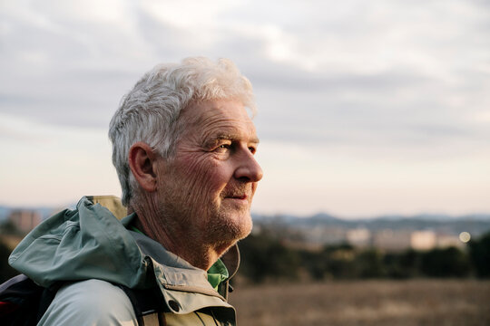Smiling senior man looking away at countryside during sunset