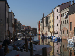 Fototapeta na wymiar Chioggia, Vena Canal with colorful buildings and crossed by bridges reflected in the water
