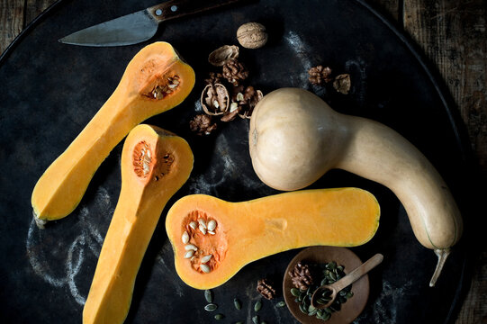 Butternut pumpkins (Cucurbita moschata), pumpkin seeds and walnuts against rustic background