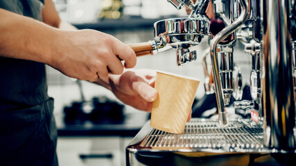 A small coffee business. Makes espresso, Americano with a takeaway. A professional barista prepares coffee in a carob coffee machine. Favorite job in the restaurant industry.