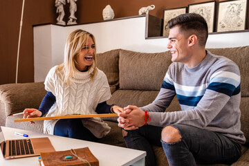 Happy female counselor with slate sitting on sofa with patient during motivation session at work place