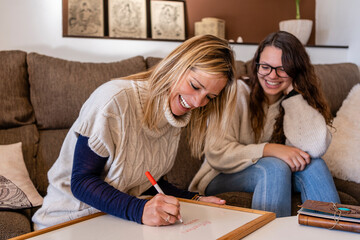 Smiling female psychologist writing on whiteboard while sitting with young woman in office
