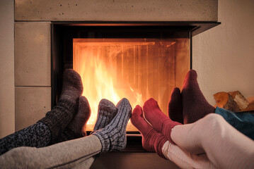 Family warming up feet in woolen socks by fireplace in living room