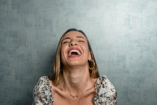 Close-up of beautiful woman with eyes closed laughing against concrete wall