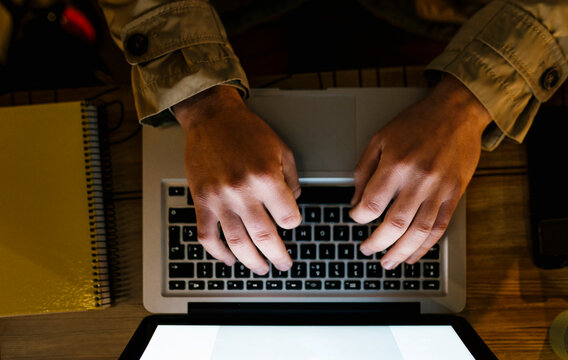 Man using laptop while sitting by table at sidewalk cafe
