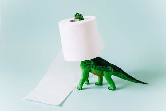 Diplodocus dinosaur toy with a roll of toilet paper around the neck on mint green background