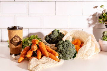Coffee to go in cork eco mug and organic veggies in mesh reusable bags on kitchen counter