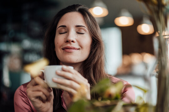 Smiling businesswoman smelling coffee in cafe
