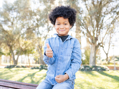 Smiling boy showing thumbs up while sitting at park