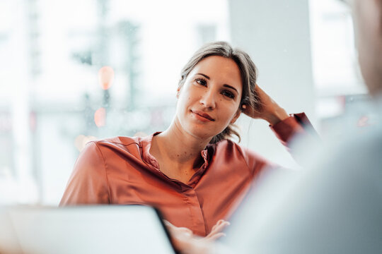 Female professional with hand in hair during meeting at coffee shop