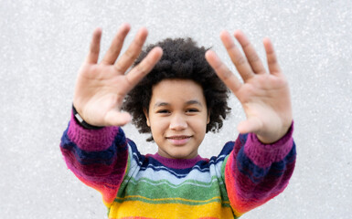 Smiling girl gesturing stop hand sign while standing against wall