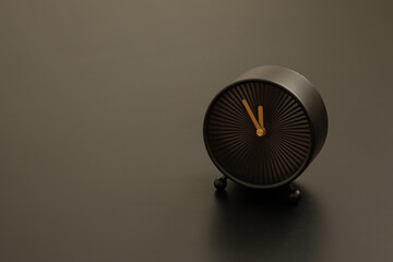 Black clock standing on black background. Text space.