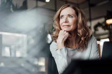 Thoughtful businesswoman with hand on chin at office