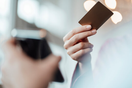 Businesswoman's hand paying through credit card to male waiter at coffee shop
