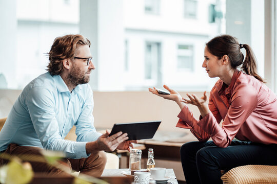 Businesswoman explaining male colleague while discussing during meeting at cafe