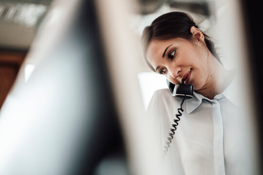 Female Entrepreneur Talking On Landline Phone At Office