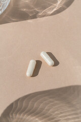 Two pills on tan background with light reflections 