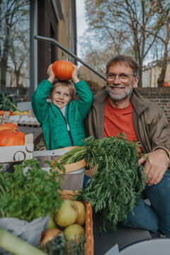 Playful son holding pumpkin while shopping with father at organic shop
