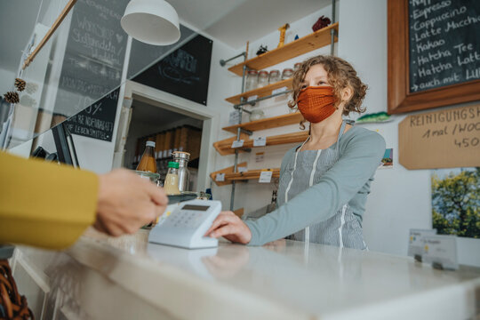 Mobile payment being made in zero waste shop by female customer during pandemic