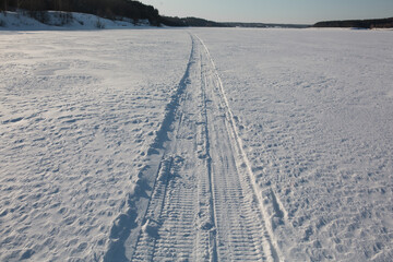 Obraz premium The trail from the snowmobile goes into the distance.