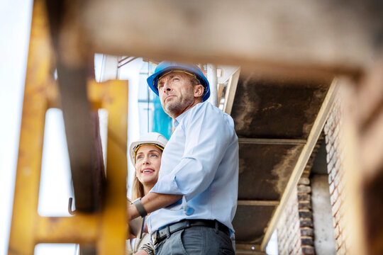 Architect looking away while standing by colleague at construction site
