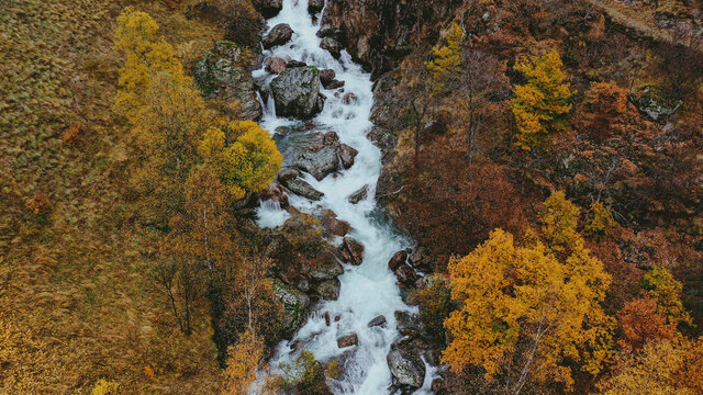 Aerial view of river splashing between rocks in autumn
