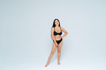 Oversized young woman wearing black bikini posing against white background