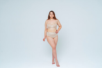 Confident woman smiling while standing with hand on hip in studio