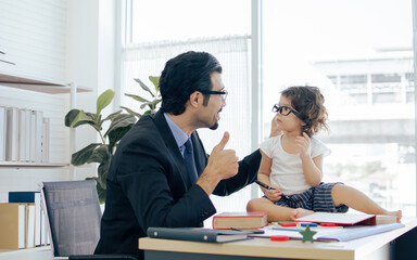 Father playing and taking care his daughter while working
