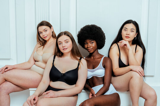 Beautiful multi-ethnic group of fashion models in lingerie against white wall