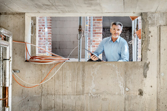 Professional smiling while using digital tablet at construction site