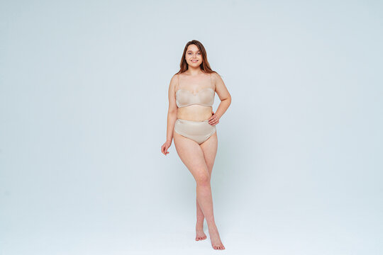 Confident woman smiling while standing with hand on hip in studio