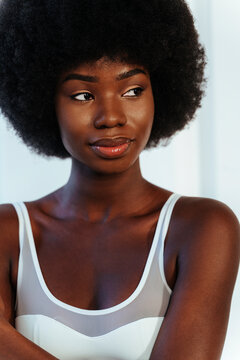 Beautiful Afro model in white bra looking away against wall