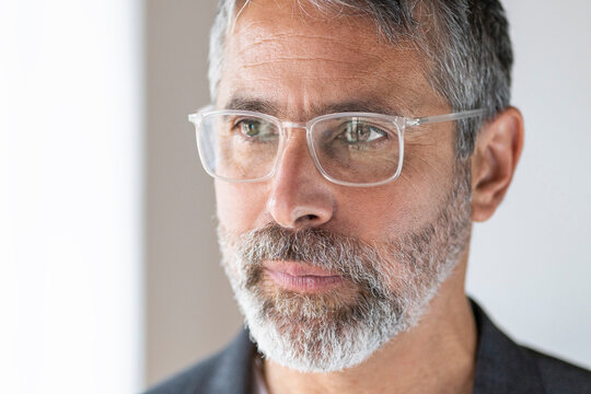 Close-up of mature businessman wearing eyeglasses looking away while standing at home