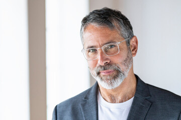 Mature entrepreneur wearing eyeglasses staring while standing at home