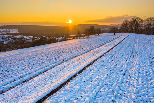 Drone view of snow-covered field at winter sunset