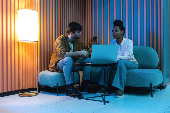 Male And Female Colleagues With Laptop Planning While Sitting In Illuminated Work Place