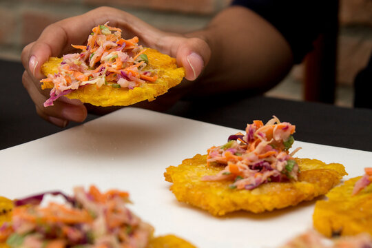 Detail of the tasting of some Tostones with grated carrot salad, cabbage, lettuce, mayonnaise. Patacones are typical in the gastronomy of the Caribbean