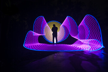 One person standing alone against a Colourful circle light painting as the backdrop