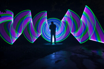 One person standing alone against a Colourful circle light painting as the backdrop